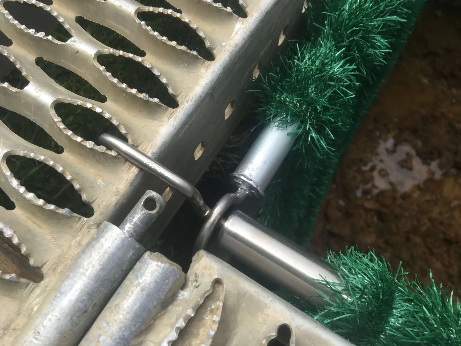 Detail der Hakenbefestigung einer Grabmatte am Grablaufrost